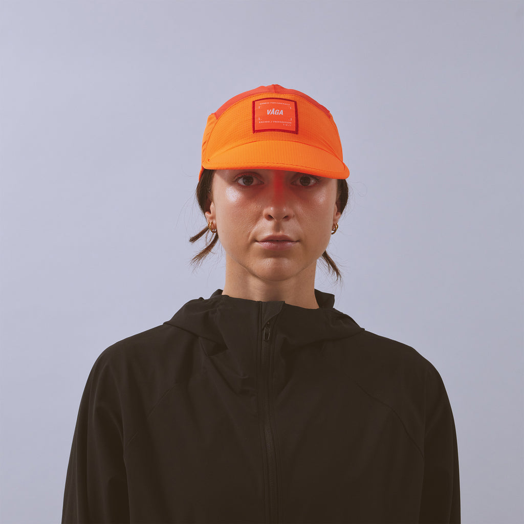 Transit Lite Cap - Neon Orange / Coral — VÅGA running cap — worn, front view